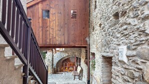 A stone building with a wooden upper level, a stone archway, and a chair in the foreground.