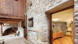 A stone-walled interior with a fireplace, wooden flooring, and a wooden bench.
