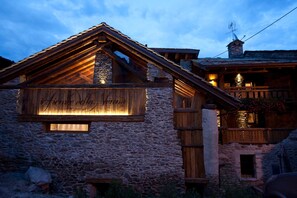 Un bâtiment en pierre doté d’un balcon en bois et d’une fenêtre éclairée.