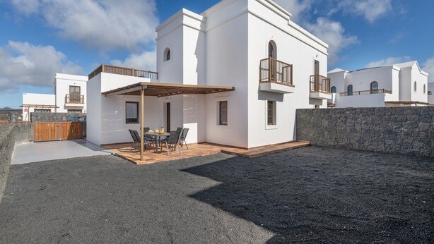 Un edificio moderno bianco con un patio, un balcone e un muro in pietra.