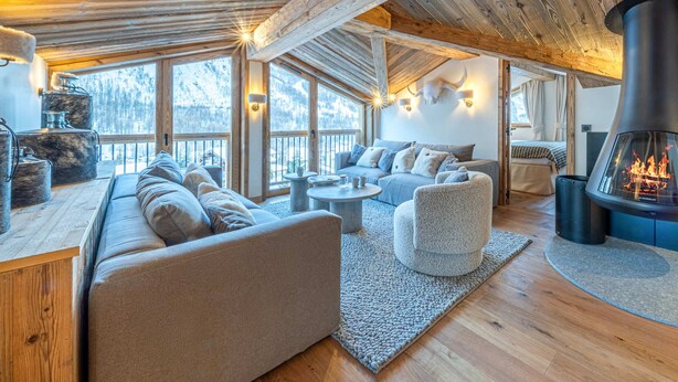 Een knus interieur met een grote open haard, houten balken en een zithoek.