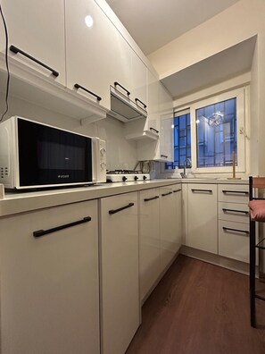 A modern kitchen with white cabinets, a built-in microwave, and a gas stove. - Besiktas1 (İstanbul)
