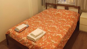 A neatly made bed with a floral bedspread, a wooden headboard, and a small bedside table with a lamp. - Besiktas1 (İstanbul)