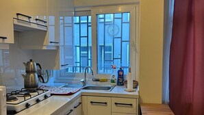 A compact kitchen with a gas stove, sink, and window. - Besiktas1 (İstanbul)