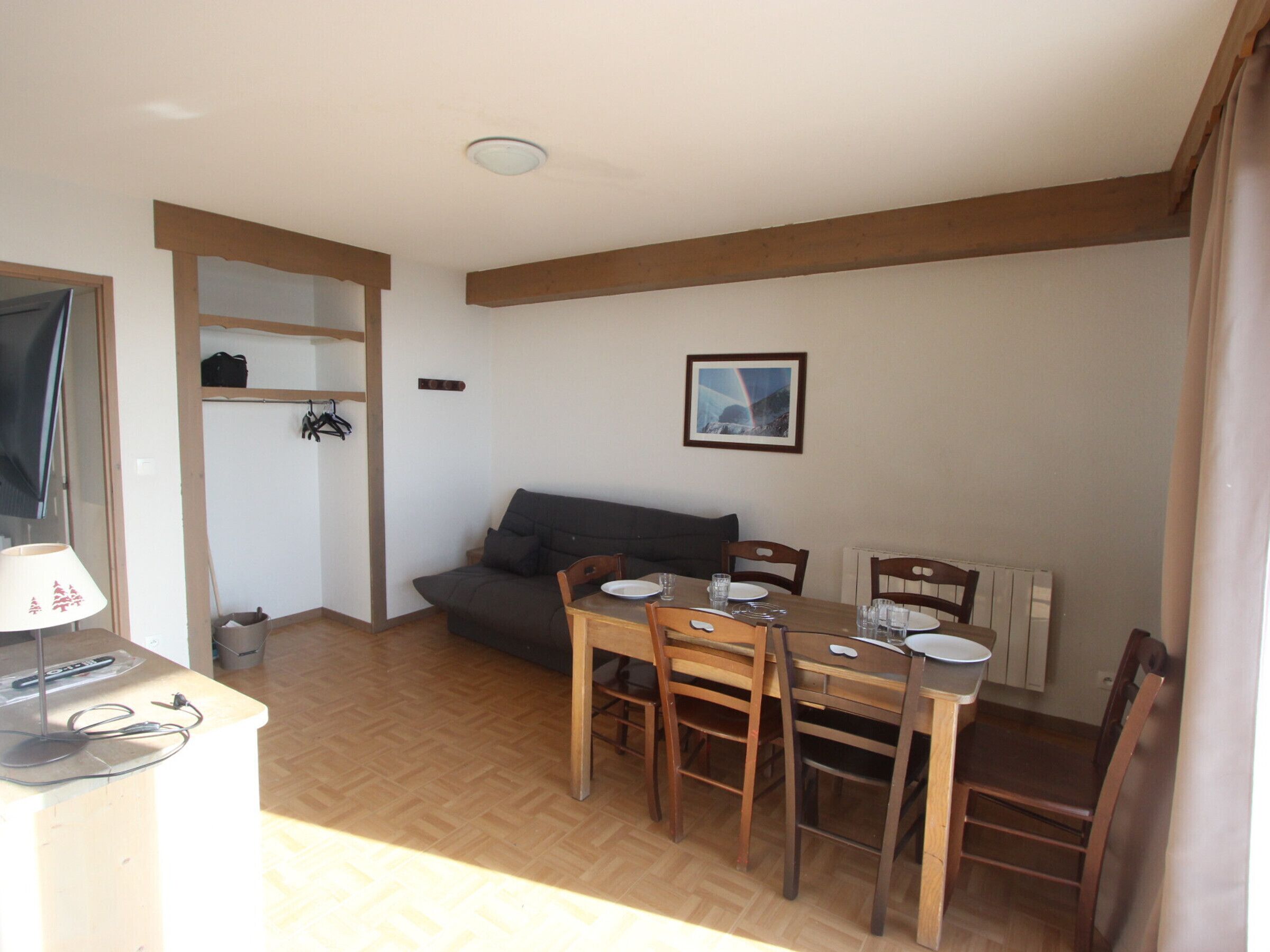 Una stanza accogliente con un tavolo da pranzo in legno, sedie, un divano e una TV.