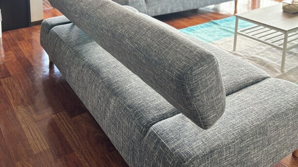 Una sala de estar moderna con un sofá gris, un comedor con una mesa y sillas, y un ventanal con cortinas.