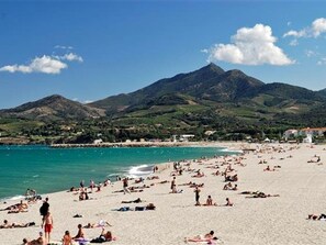 A beach with people sunbathing and swimming, a mountain in the background, and a clear blue sky. - Bright T2 Apartment - 200m from Beach, 4 pax (Argelès-sur-Mer)