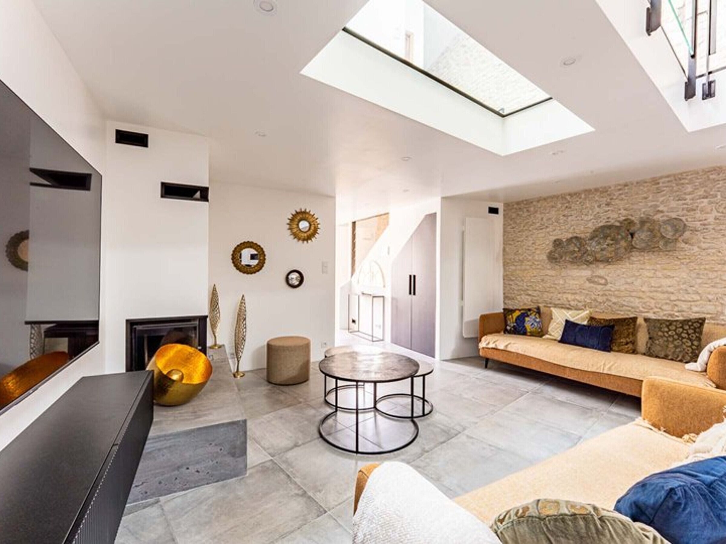 A modern living room with a stone wall, a sofa, a coffee table, and a TV.