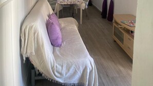 Et hyggeligt værelse med en sofa, et spisebord og et lille træskab.