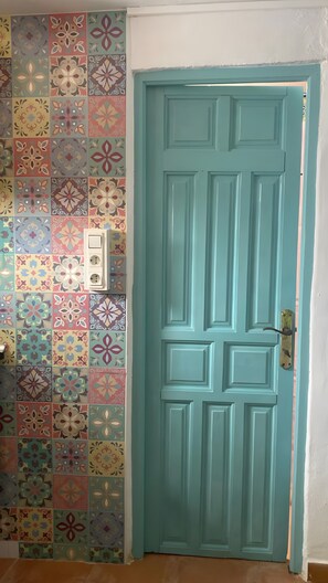 A teal door with a patterned wall behind it.