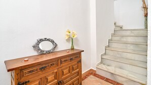 Ein hölzerner Kommode mit Schubladen, ein Spiegel und eine Vase mit Blumen vor einer weißen Wand.