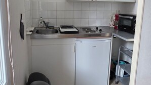 Eine kompakte Küche mit Kühlschrank, Herd, Mikrowelle und Spüle.