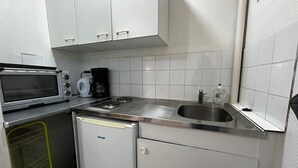 Eine kompakte Küchenzeile mit Mikrowelle, Kaffeemaschine, Spüle und kleinem Kühlschrank.