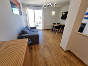 A modern living room with a grey sofa, a wooden coffee table, and a dining area with a table and chairs. - Charming apartment in L'Escala, near the port and beach (L'Escala)