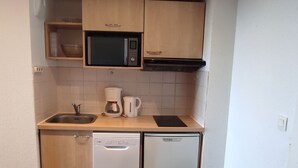 A compact kitchen with a microwave, coffee maker, sink, and dishwasher. - Calm apartment in Super Besse, 5 people, parking and pool (Besse-et-Saint-Anastaise-Super Besse)