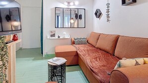 Ein modernes Wohnzimmer mit einer großen Couch, einem kleinen Beistelltisch, einem Spiegel und einem Fernseher.