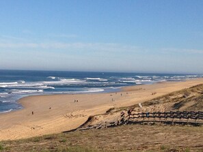 A beach with a wooden fence and a clear view of the ocean.