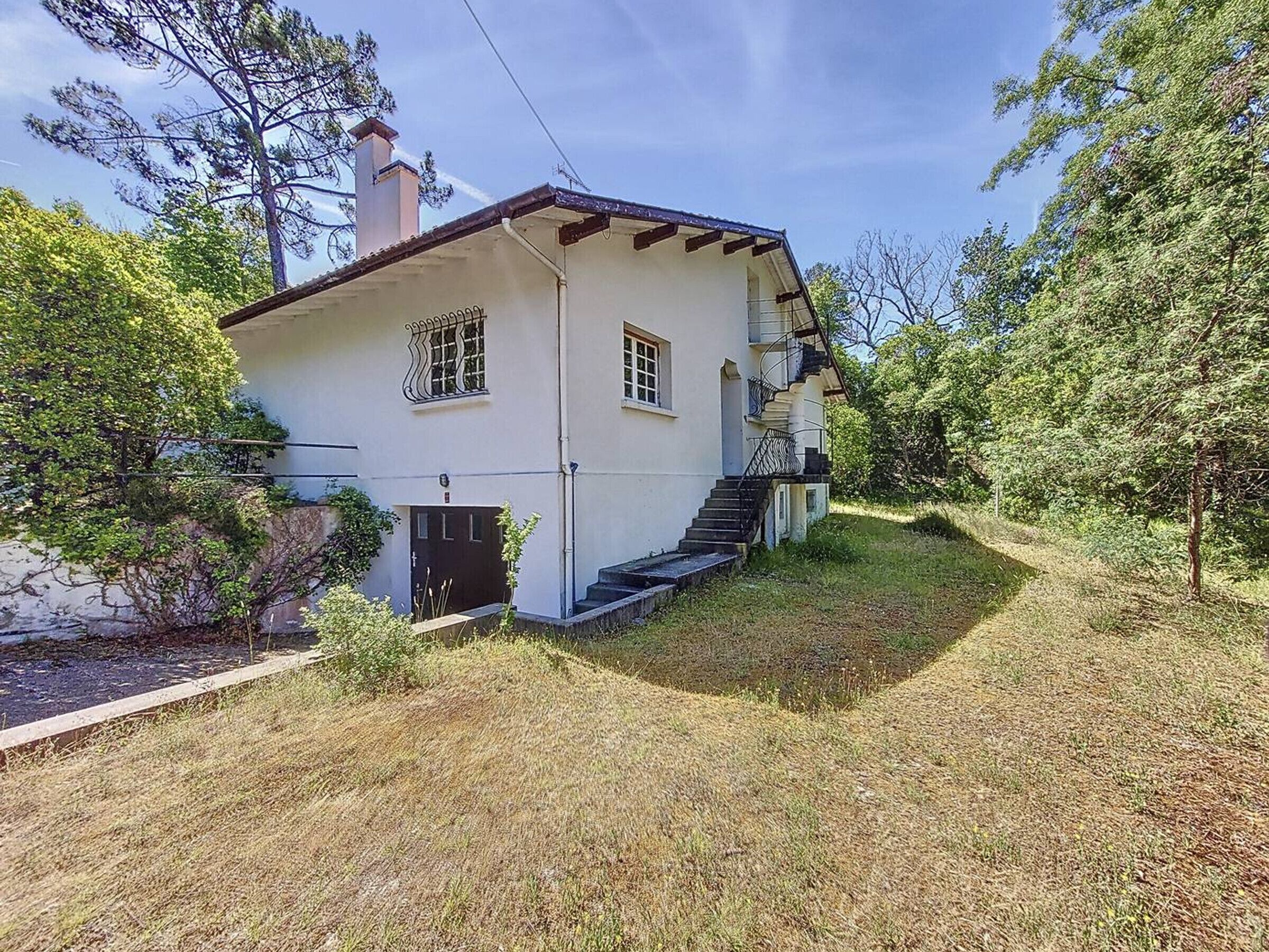 Een wit huis met een zwarte deur, een klein raam en een trap naar een veranda.