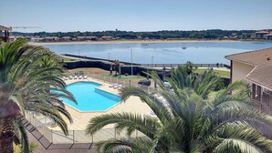 Uma área de piscina com vista para uma praia e um corpo d'água.