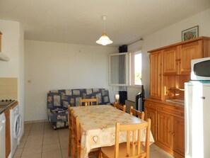 A compact kitchen with a dining table, wooden cabinets, and a washing machine. - 3-room apartment with loggia, near the sea, 6 sleeps - Bormes-les-Mimosas (Bormes-les-Mimosas)