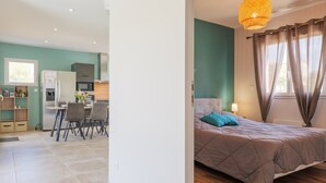 A modern bedroom with a bed, curtains, and a hanging light fixture. - Villa "Gîte Des Clapas – Lisa" with Wi-Fi and Air Conditioning (Balazuc)