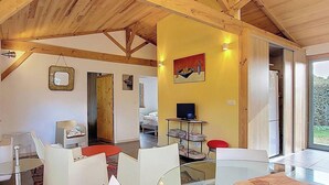 Um interior moderno com teto alto, mesa de vidro e uma parede com detalhes amarelos.