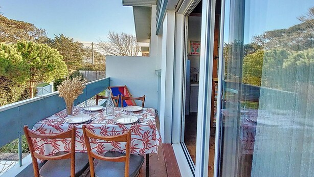 Ein Balkon mit Esstisch, der auf einen Garten und ein Gebäude mit einem Schild blickt.