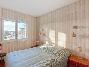 A bedroom with a bed, a window, and wooden walls. - T3 near beach with terrace and Wi-Fi for 4 people (Vieux-Boucau-les-Bains)