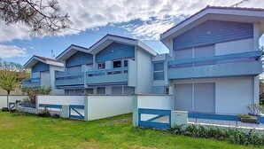 Ein modernes Wohngebäude mit zwei Etagen, flachem Dach und einem Balkon im oberen Geschoss.
