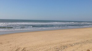 Ein Strand mit breitem Sandstrand und sanften Wellen.