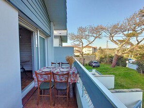 A balcony with a table set for dining, chairs, and a decorative vase. - T3 near beach with terrace and Wi-Fi for 4 people (Vieux-Boucau-les-Bains)
