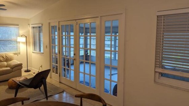 Un salon comprenant un canapé, une table basse et une table à manger. Des portes-fenêtres coulissantes donnent accès à un espace extérieur.