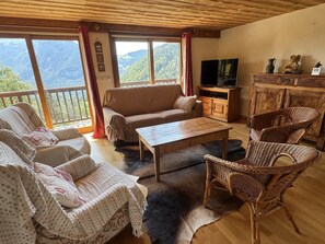 A cozy living room with a sofa, chairs, a coffee table, and a TV. - Spacious 160m² Apartment - 3 Bedrooms - 10 Guests - Private Parking, WiFi (Arâches-la-Frasse)
