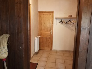 A hallway with a wooden door, a radiator, and a clothes rack with hangers. - Spacious 160m² Apartment - 3 Bedrooms - 10 Guests - Private Parking, WiFi (Arâches-la-Frasse)