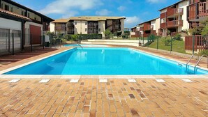 Una piscina con borde de ladrillo, rodeada de edificios residenciales de varios pisos con balcones.