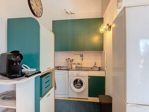 A compact kitchen with teal cabinets, a washing machine, a coffee maker, and a sink. - 2-Bedroom Apartment for 6 Guests with Pool (Vieux-Boucau-les-Bains)