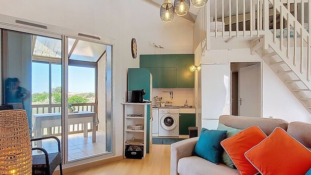 Una sala de estar moderna con sofá, comedor y cocina.