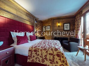 A hotel room with a wooden headboard, a bed with a patterned bedspread, a seating area with a sofa and armchairs, and a small table. - Courchevel 1850, 4 rooms, 8 ppl, ski-in/ski-out, parking (Courchevel)