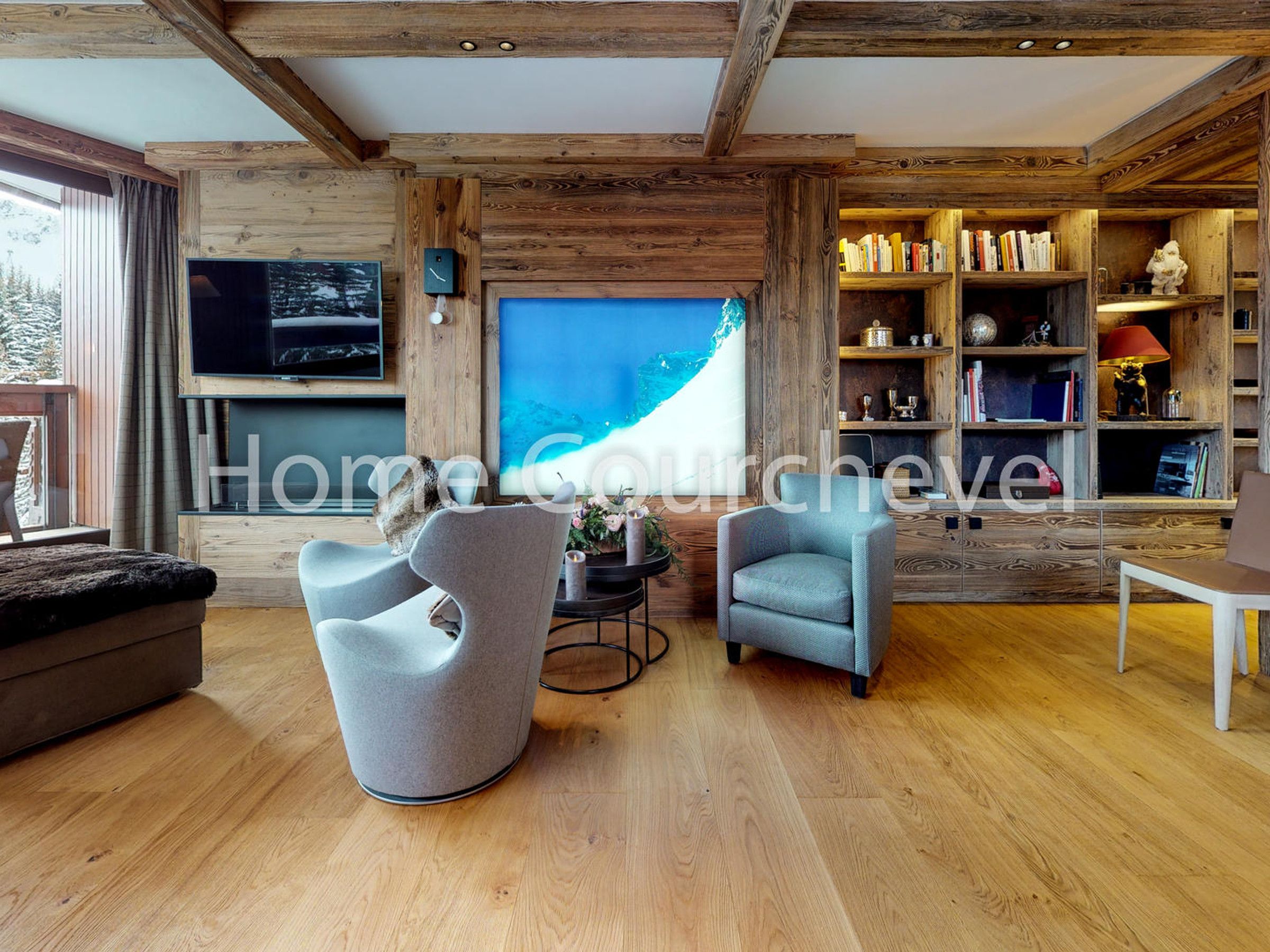 Un soggiorno moderno con travi in legno, una grande televisione e una libreria.