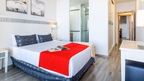 Moderni hotellihuone, jossa on suuri sänky, työpöytä ja erillinen vaatehuone.
