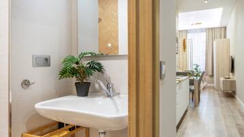 Een moderne badkamer met een witte wasbak, een potplant en een plank met houten frame.