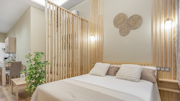 Ein Schlafzimmer mit Bett, Schreibtisch und einer Pflanze.