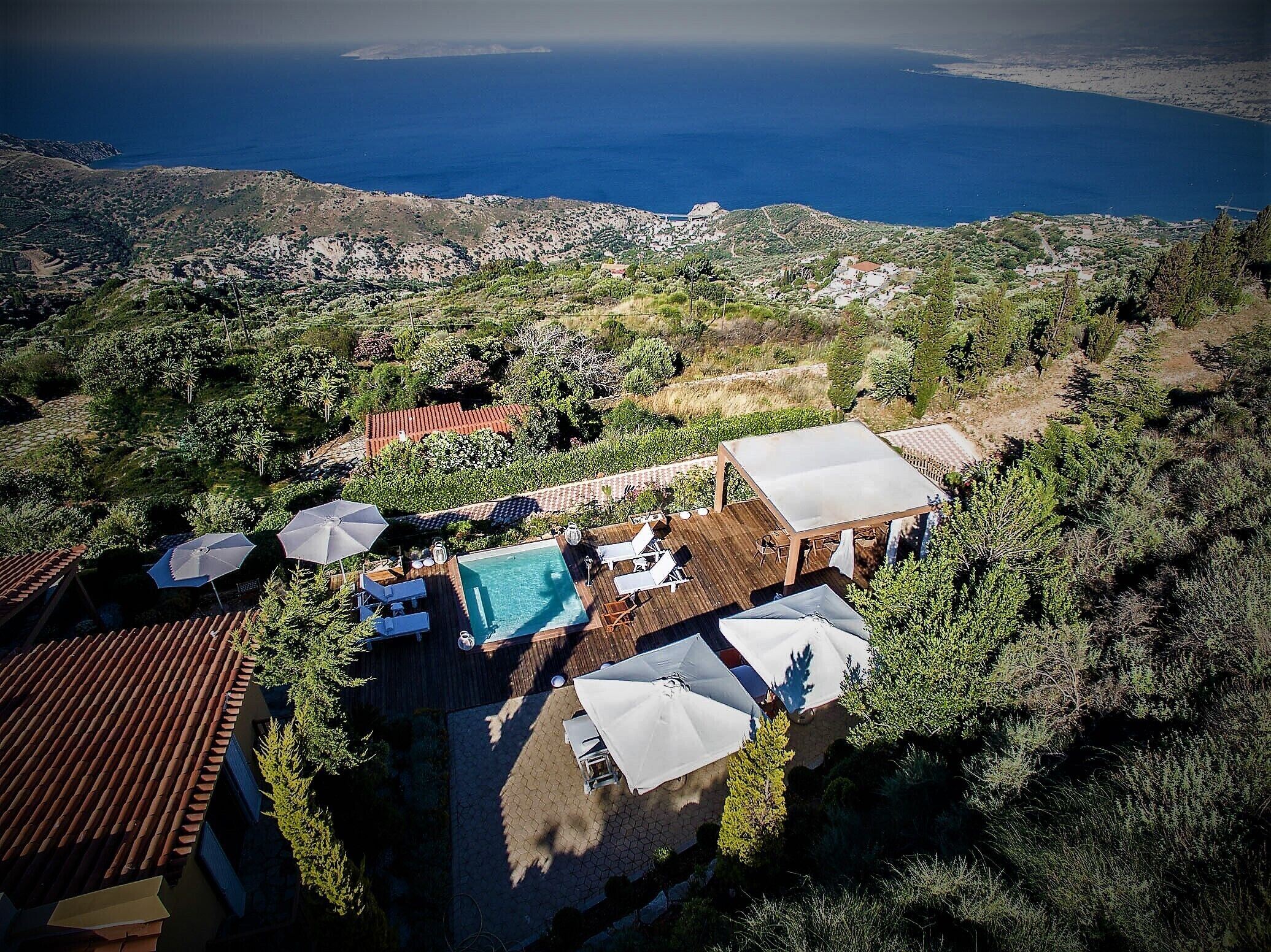 Ein Luftbild eines Anwesens mit Swimmingpool, Außenbereich zum Sitzen und Blick auf das Meer.