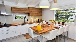 Eine moderne Küche mit weißen Schränken, einer Holz Arbeitsplatte und einem großen Fenster.