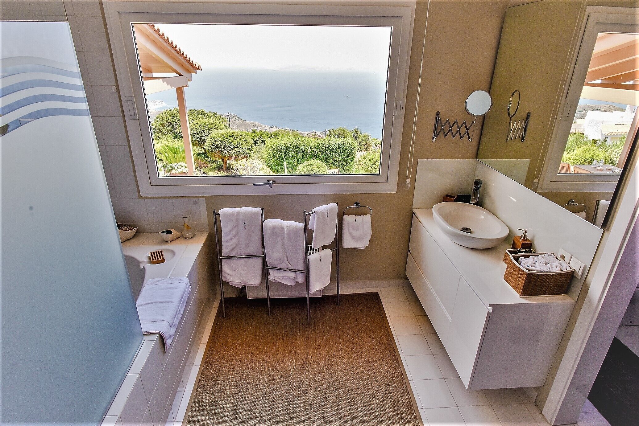 Un baño con un ventanal grande, un lavabo y un espejo.