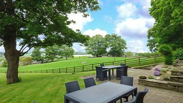 A patio area with a table and chairs, surrounded by a stone wall and a wooden fence.