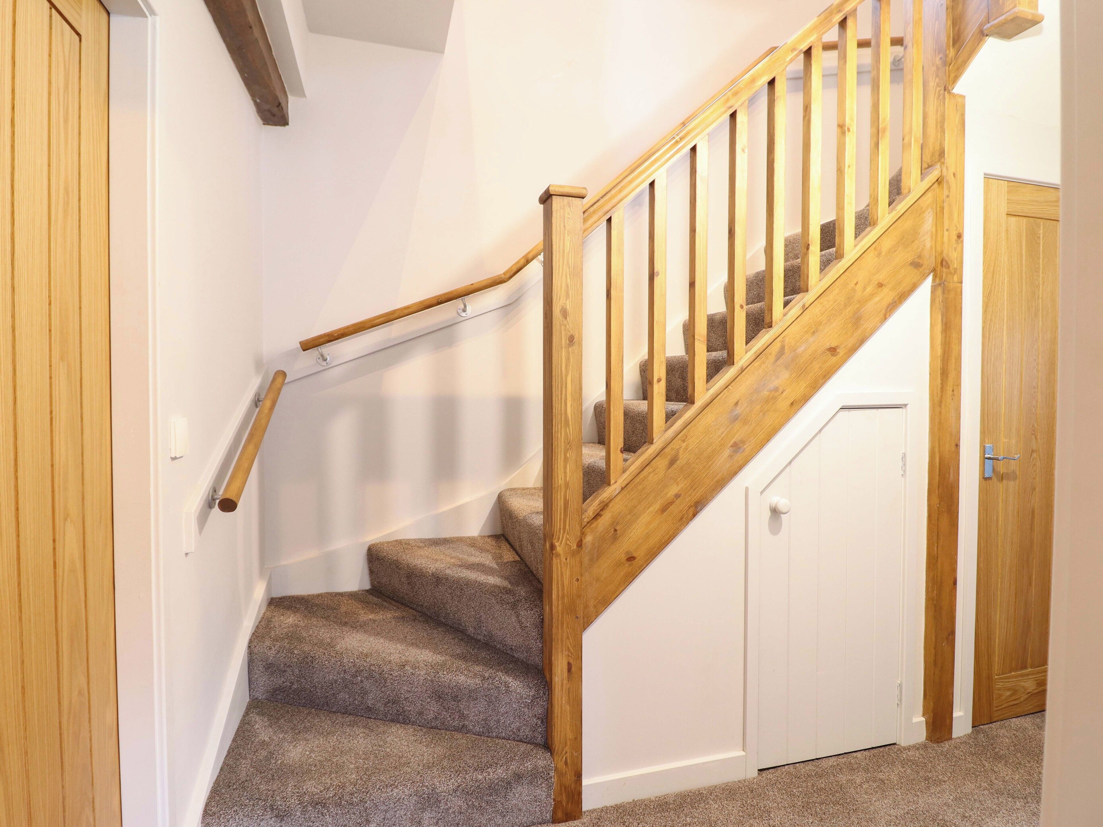 A wooden staircase with carpeted steps leading to a white door.