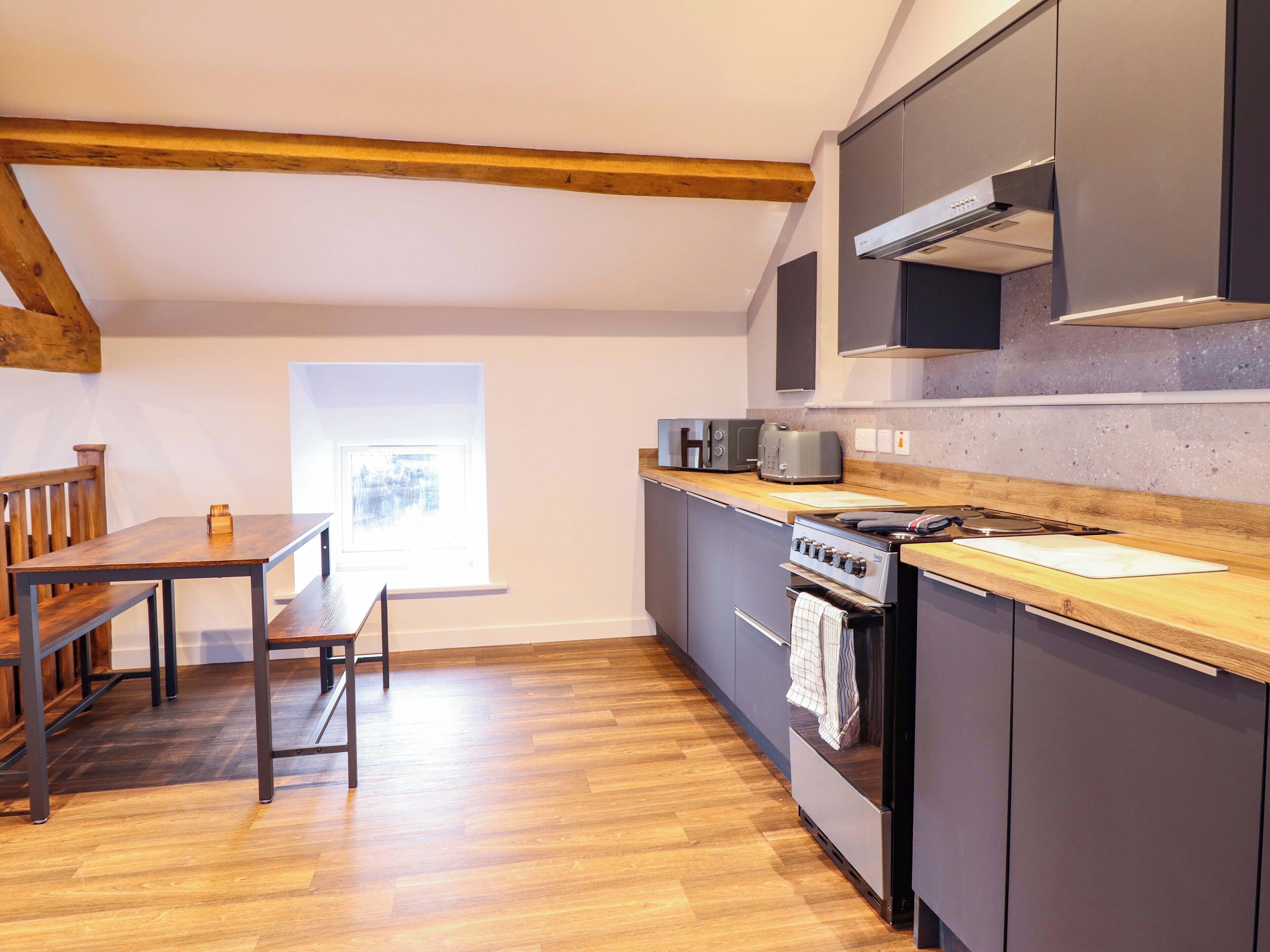 A kitchen with a wooden table, chairs, a window, and modern appliances.