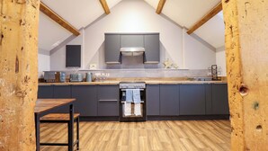 A modern kitchen with dark cabinets, a wooden countertop, and a built-in oven. - Clegir Bach (Corwen)
