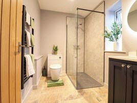 Un baño moderno con cabina de ducha de vidrio, inodoro, lavabo y una planta en maceta.